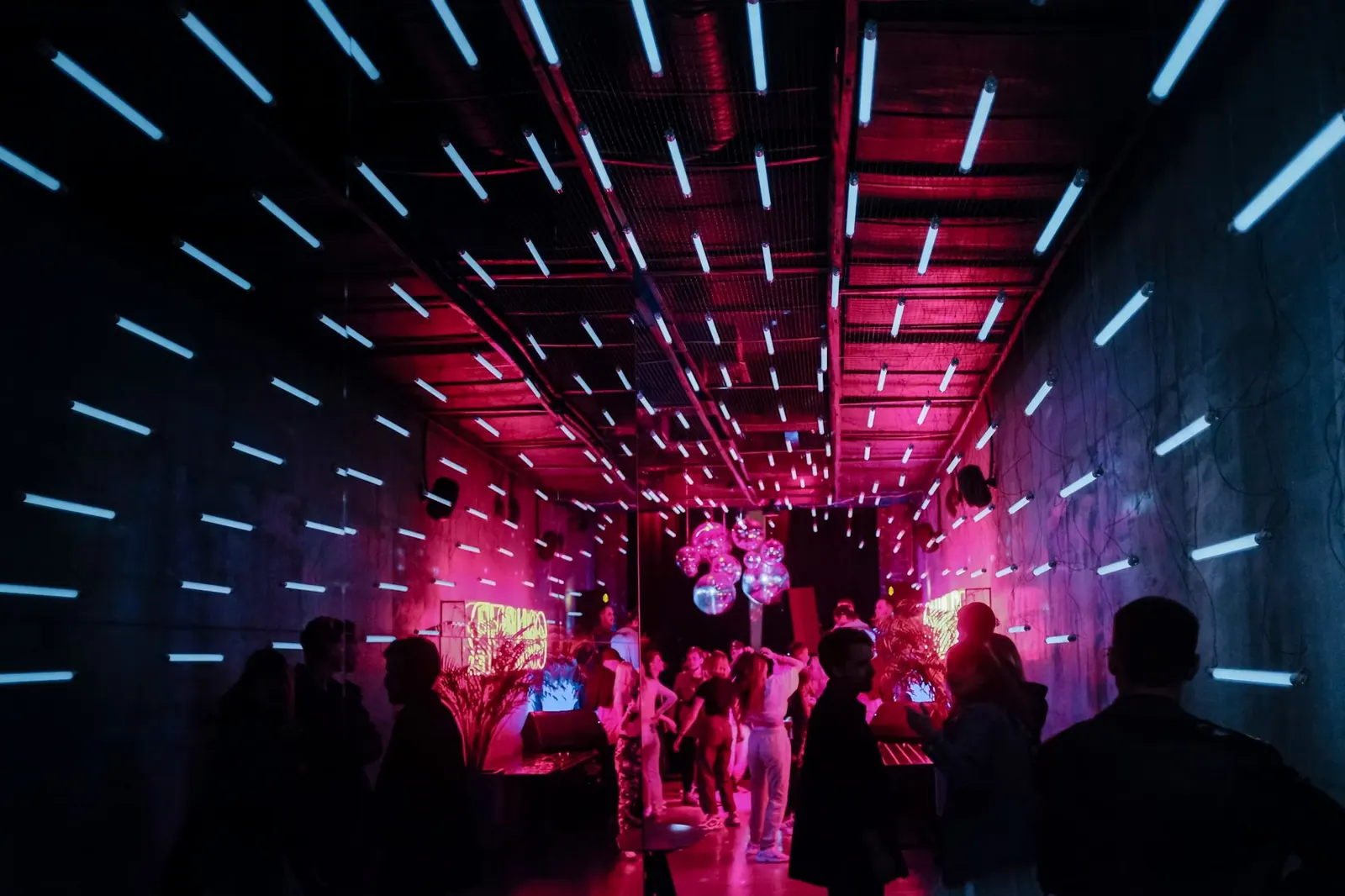 Sala iluminada en rosa con gente bailando